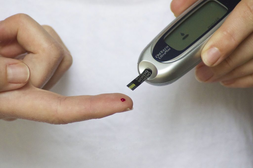 Na zdjęciu wykonywane jest pomiar cukru we krwii przy pomocy specjalnego urządzenia.