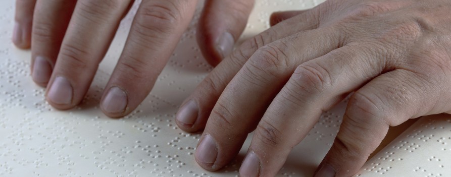 Dłonie odczytujące kartę zapisaną Alfabetem Braille'a.