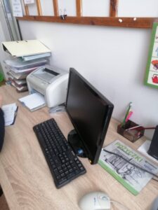 biurko nauczyciela - na nim czarny komputer i dużo dokumentów