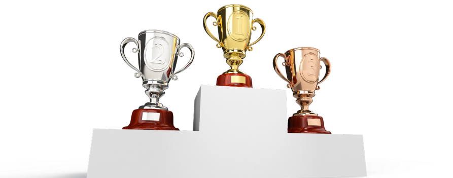 Zwycięskie podium dla pierwszych trzech miejsc, na każdym stoi puchar w kolorze złota dla 1 miejsca, srebra dla 2 miejsce, brązu dla 3 miejsca.