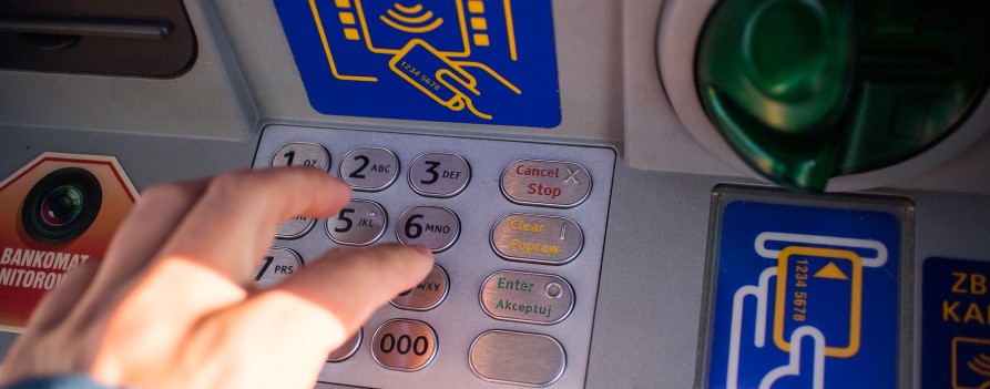 Klawiatura bankomatu, widać dłoń, która naciska klawisz