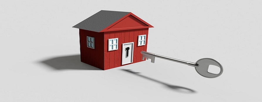 Model małego domku, obok przed nim nieproporcjonalnie wielki klucz celujący w małe drzwi domku.