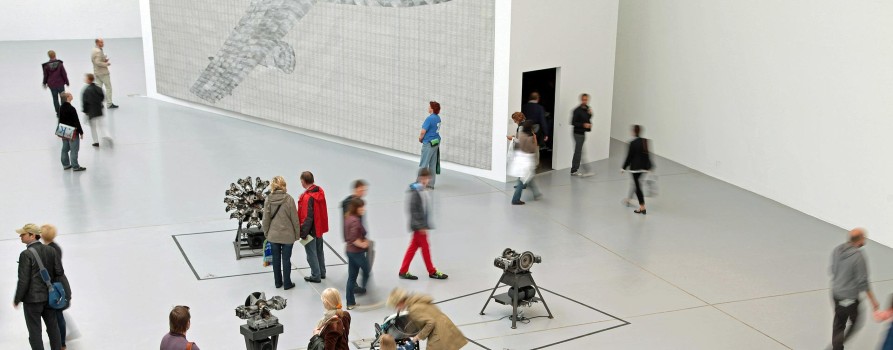 Ludzie spacerujący po dużej, jasnej sali wystawowej w muzeum.