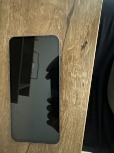 Samsung Galaxy A55 (przód telefonu, zgaszony ekran, widać ramki i odbicie otoczenia)