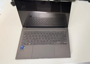 Na białym blacie otwarty ultrabook Asus Zenbook S14 w kolorze ciemno szarym.…<p class=