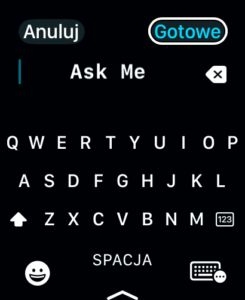 Okno aplikacji Chat GPT na Apple Watch. Widoczna jest klawiatura ekranowa. Tło jest czarne, a litery białe W polu tekstowym tekst Ask Me